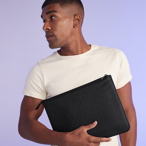 May include: A black zippered pouch with a smooth, textured surface. The pouch is held by a person wearing a white t-shirt.