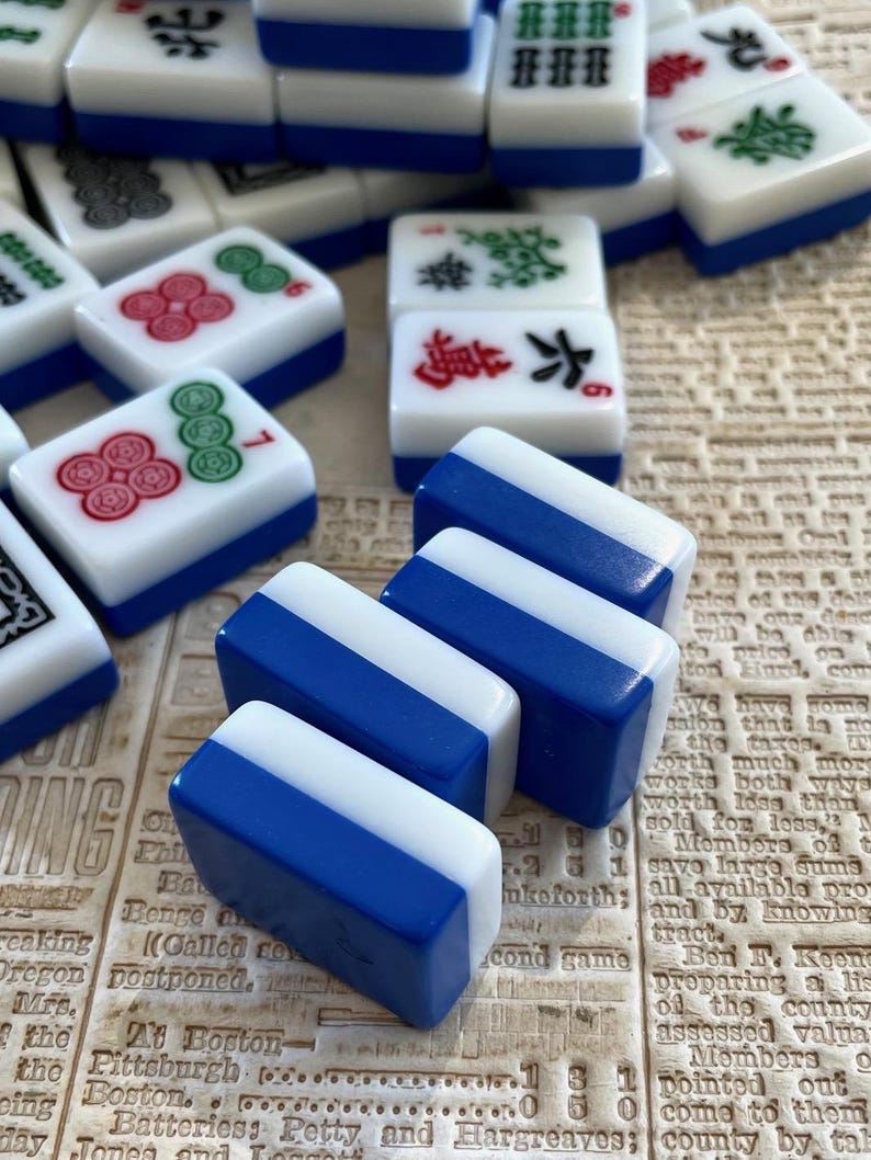 May include: Three blue and white mahjong tiles with white and red Chinese characters. The tiles are stacked on top of each other.