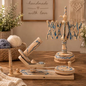 May include: A wooden yarn ball winder and a matching wooden yarn swift, both featuring a natural light wood finish with intricate blue lightning-like patterns. The winder includes a crank handle, a spool, and a guide, while the swift is upright.