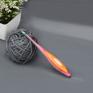 May include: A ball of gray yarn and a pink, orange, and green crochet hook.