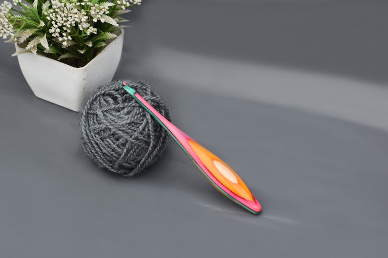 May include: A ball of gray yarn and a pink, orange, and green crochet hook.