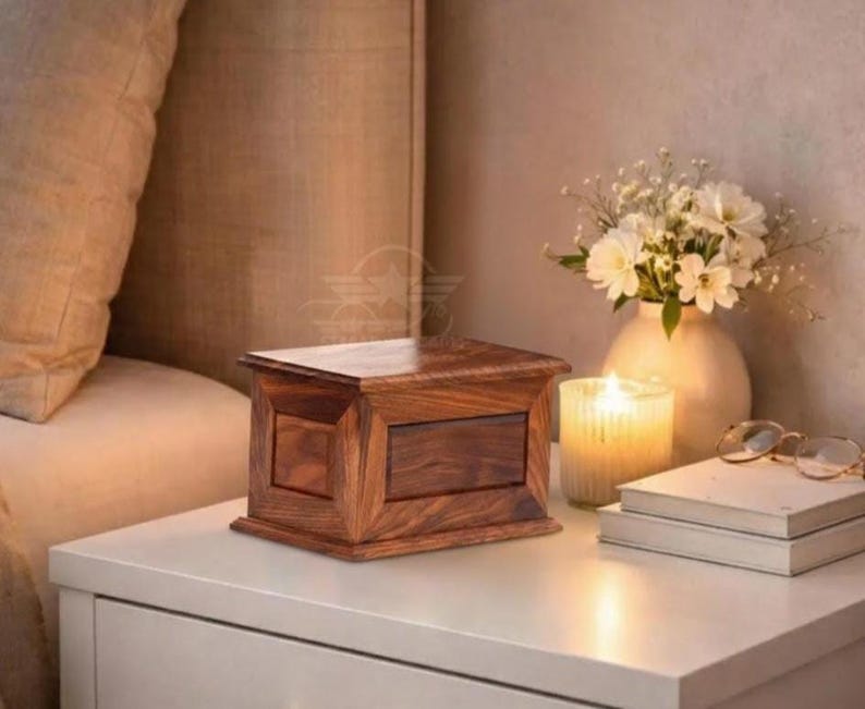 May include: A rectangular wooden box with a rich brown grain pattern and a smooth, polished finish. The box features a flat lid and a structured, paneled design on its sides, showcasing the natural wood texture and deep, warm color tones throughout.