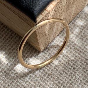 Peut inclure: Une fine bague en or poli avec un anneau circulaire lisse. La surface métallique est réfléchissante et de couleur uniforme, présentant un design simple et continu sans aucune pierre précieuse, gravure ou élément décoratif sur l'anneau.