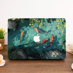 Könnte beinhalten: Eine Laptop-Haut mit einem Design von Koi-Karpfen, die in einem Teich mit grünem Laub und Steinen schwimmen. Die Haut ist für ein Macbook konzipiert.