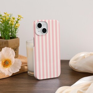 May include: A pink and white striped phone case for an iPhone with a camera cutout.