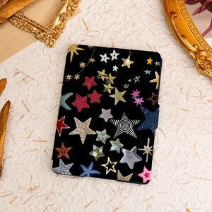 May include: A black e-reader cover with a colorful star pattern. The stars are in various sizes and colors, including red, blue, gold, and silver.