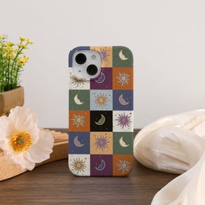 May include: A colorful phone case featuring a patchwork design with sun and moon motifs in various colors. The case has a square pattern with alternating squares of different colors, including blue, orange, and purple.