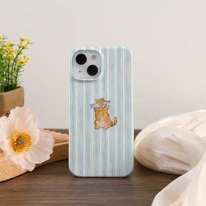 Könnte beinhalten: Handyhülle mit hellblau-weißem Streifenmuster. Sie zeigt eine Aquarellillustration einer orangefarbenen Tabby-Katze, die einen Fisch im Maul hält. Die Hülle hat einen Ausschnitt für Kamera und Blitz.