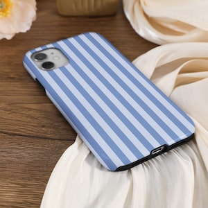 May include: A blue and white striped phone case for an iPhone. The case has a camera cutout and a charging port cutout.