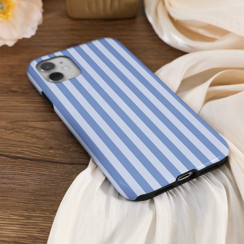 May include: A blue and white striped phone case for an iPhone. The case has a camera cutout and a charging port cutout.