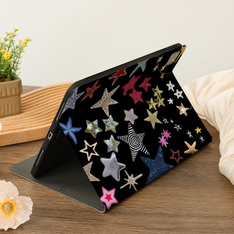 Pu&ograve; includere: Una custodia nera per iPad con un motivo a stelle colorate. Le stelle sono di varie forme e dimensioni e sono disposte in modo casuale. La custodia &egrave; realizzata in un materiale resistente ed &egrave; progettata per proteggere il tuo iPad da graffi e urti.