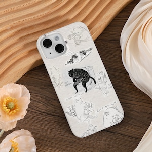 Puede incluir: Una funda de teléfono blanca con una ilustración en blanco y negro de gatos. Los gatos están realizando diversas actividades, como comer donuts, ir de compras y beber. El texto en la funda incluye "Eat Donut", "Happy Shopping", "Just Happens" y "My Day".