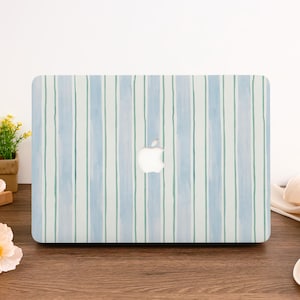 Op de afbeelding: Een laptophoes met een aquarelstreepontwerp in blauw- en groentinten. De hoes heeft een wit Apple-logo in het midden. De achtergrond is een houten oppervlak.
