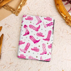 May include: Pink and white e-reader case with a pattern of cowboy boots and hats.