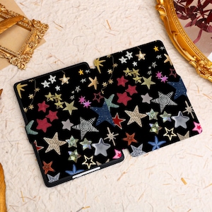 May include: A black e-reader case with a colorful star pattern. The stars are in various sizes and colors, including red, blue, gold, and pink.