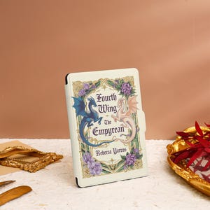 May include: A white Kindle Paperwhite e-reader cover with a floral design and two dragons. The cover features the text "Fourth Wing The Empyrean" and the author's name "Rebecca Yarros".