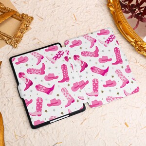 May include: A pink and white patterned Kindle cover with a design of cowboy boots and hats.