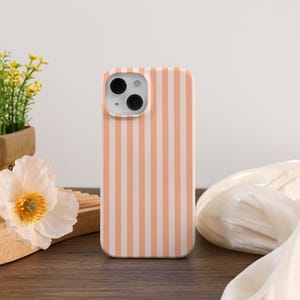 Peut inclure: Une coque de téléphone rayée rose et blanche pour un iPhone.