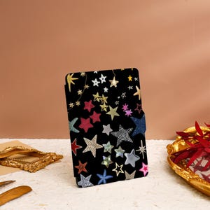 May include: A black e-reader case with a colorful star pattern. The stars are in various sizes and colors, including gold, silver, red, blue, and green.