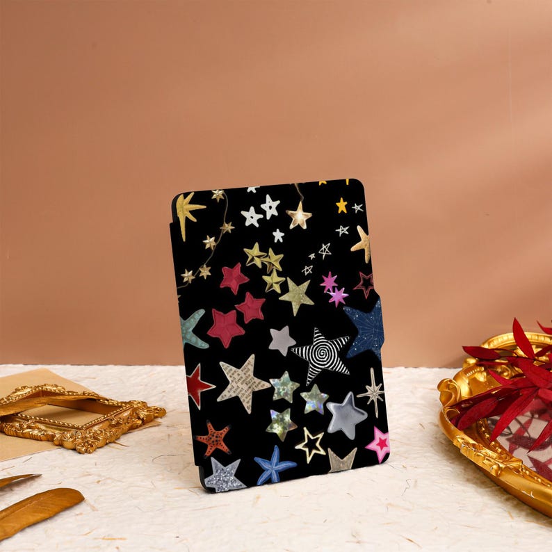May include: A black e-reader case with a colorful star pattern. The stars are in various sizes and colors, including gold, silver, red, blue, and green.