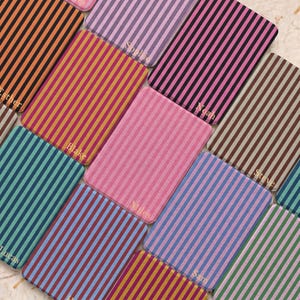 May include: A selection of rectangular items with vertical stripes in shades of pink, orange, and blue. Each item is personalised with a name, such as "Blake" and "Miles". The items are arranged in a grid pattern.
