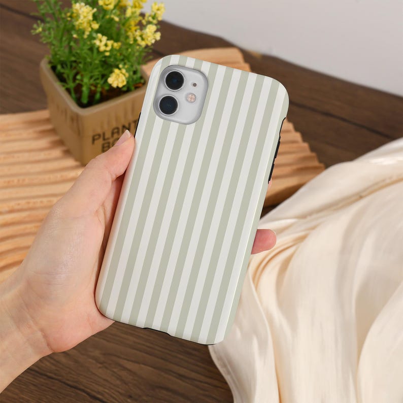 May include: A phone case with a vertical striped pattern in light green and white. The case has a smooth finish and covers the back and sides of the phone. The phone case has a camera and flash opening.