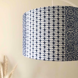 May include: A white and blue patterned lampshade with a geometric design. The lampshade is made of fabric and has a cylindrical shape.