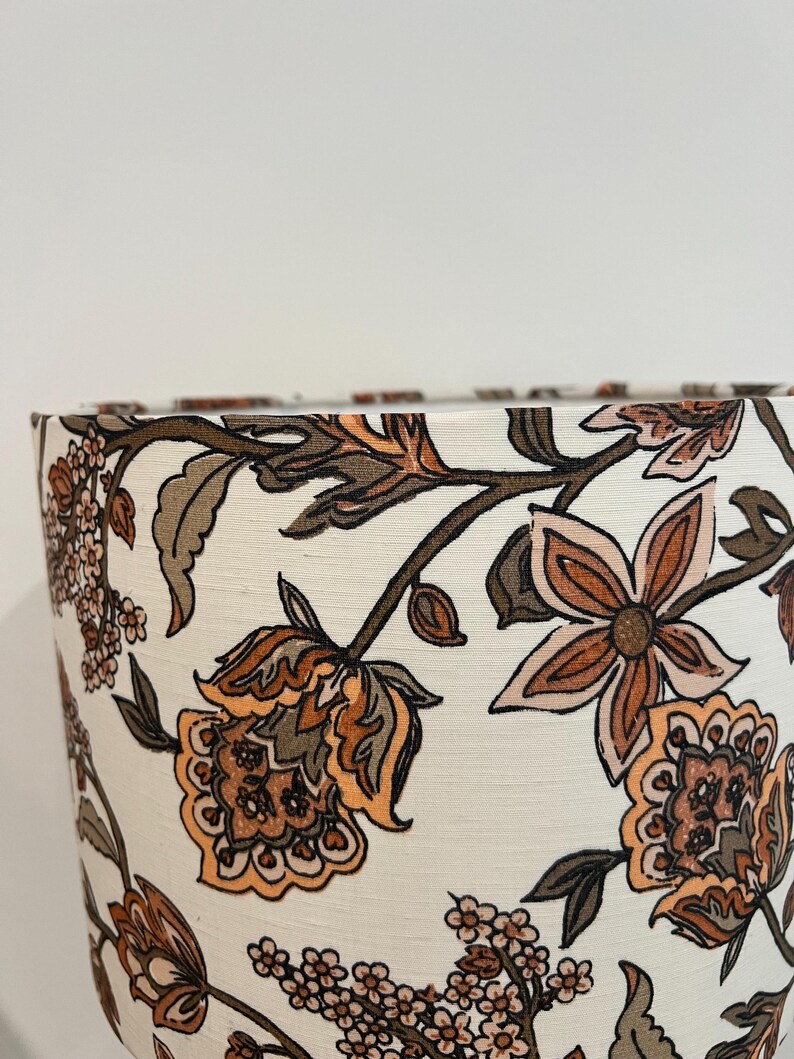 May include: A white lampshade with a floral pattern in shades of brown, orange, and pink. The flowers are stylized and have a paisley-like design.