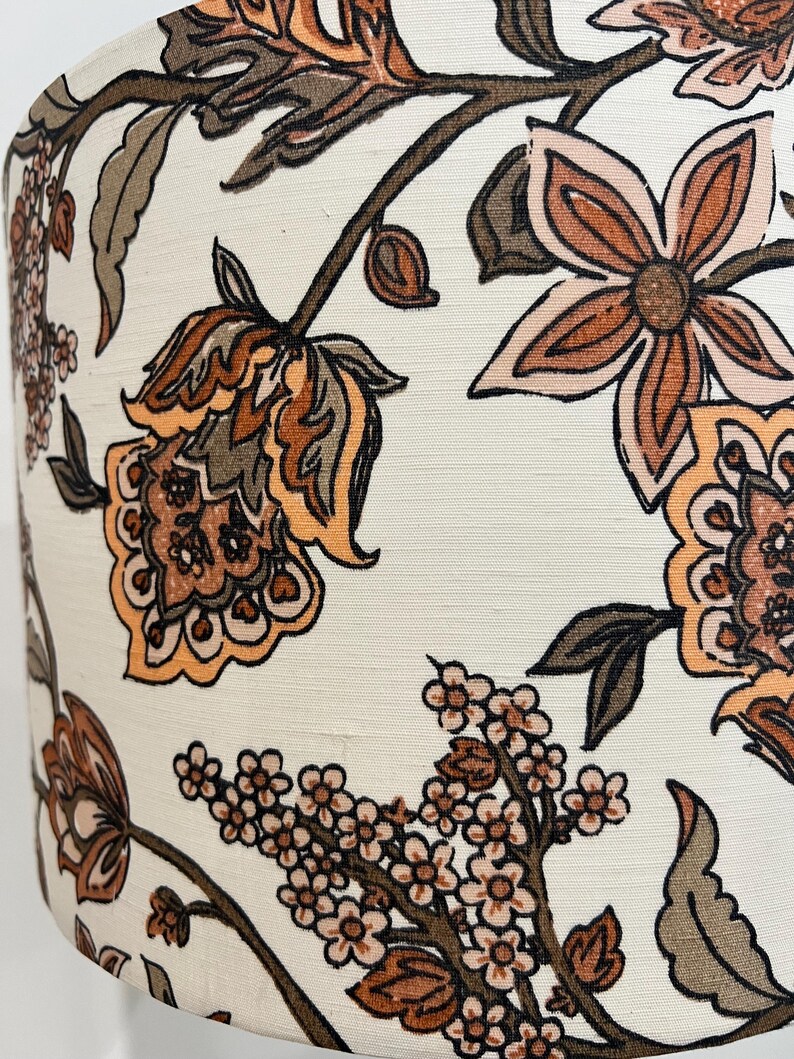 May include: A white lampshade with a floral pattern in shades of brown, orange, and pink. The flowers are stylized and have a vintage feel.