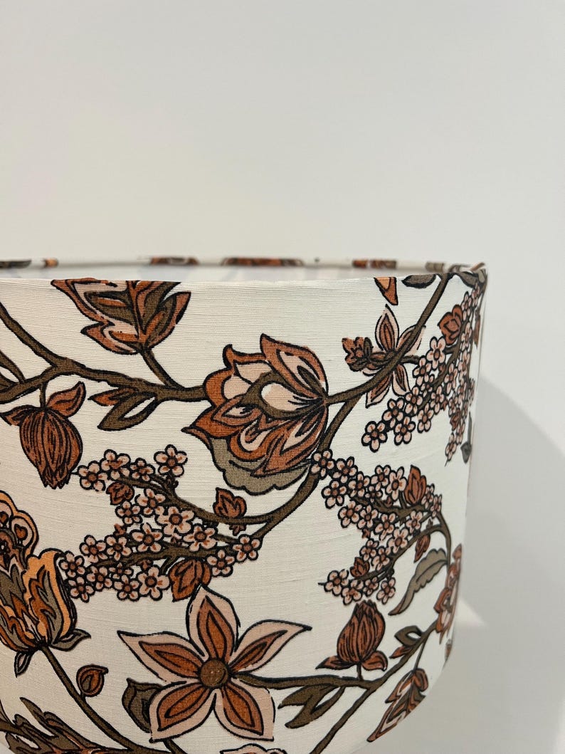 May include: A white lampshade with a floral pattern in shades of brown, pink, and green. The pattern features stylized flowers and leaves.