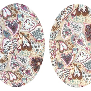 May include: Two oval-shaped placemats with a paisley pattern in shades of brown, pink, and blue on a beige background.