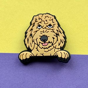 May include: A brown and white cartoon doodle dog with a pink tongue sticking out, peeking over a black surface. The dog has a serious expression on its face.