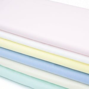 Puede incluir: Conjunto de seis muestras de tela apiladas en colores pastel. Los colores son rosa, blanco, amarillo, azul claro, crema y verde claro.