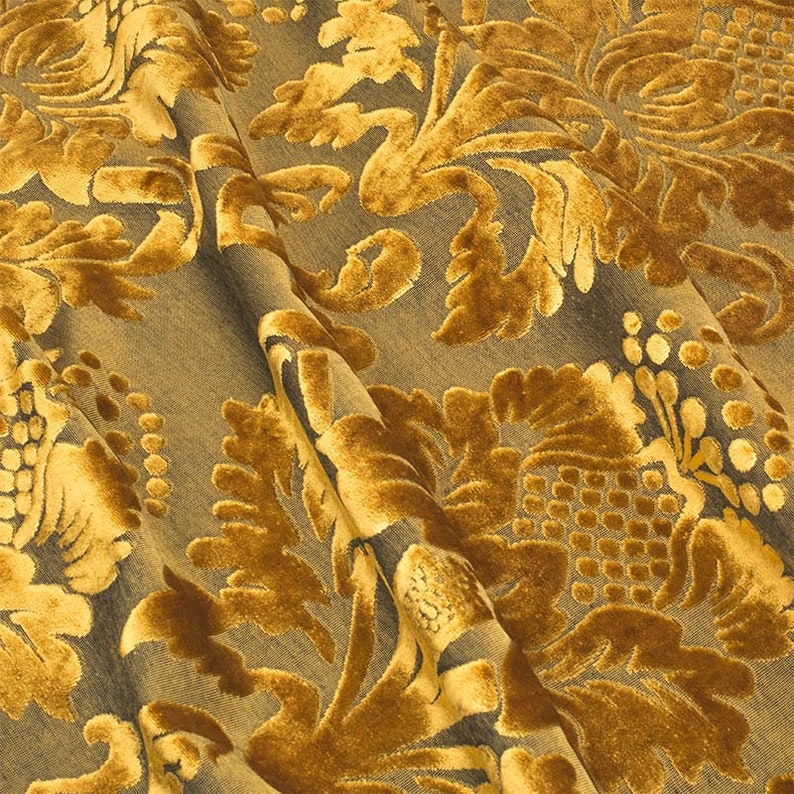 May include: A close-up of a gold fabric with a damask pattern. The fabric has a raised texture and a subtle sheen.