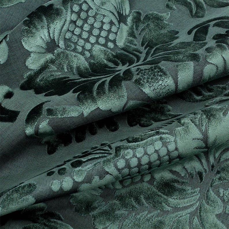 May include: Close-up of a dark green fabric with a raised floral pattern. The fabric has a soft, velvety texture.