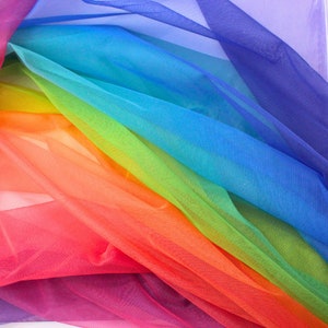 Può includere: Tessuto di tulle color arcobaleno in diverse tonalità di rosso, arancione, giallo, verde, blu e viola. Il tessuto è trasparente e delicato, con una texture morbida e fluida.