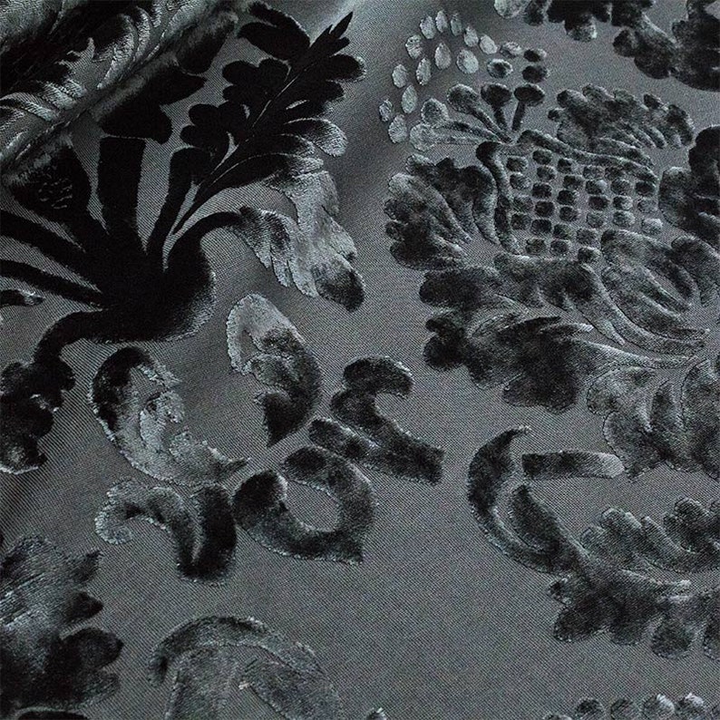 May include: Black velvet fabric with a raised floral pattern. The fabric has a gray background and the flowers are a darker shade of gray.