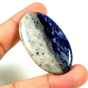 Puede incluir: Una piedra preciosa cabuj&oacute;n ovalada lisa con un patr&oacute;n blanco y azul. La parte blanca tiene un aspecto moteado, mientras que la parte azul tiene un color m&aacute;s oscuro y s&oacute;lido.