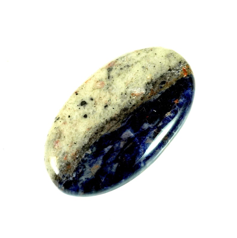 Puede incluir: Una piedra lisa de forma ovalada con la parte superior blanca y gris y la parte inferior azul oscuro. La piedra tiene un acabado natural y pulido.