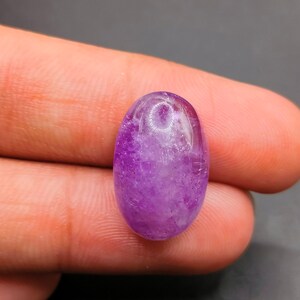 Könnte beinhalten: Ein ovaler Amethyst-Edelstein in violetter Farbe mit einer trüben, durchscheinenden Optik.