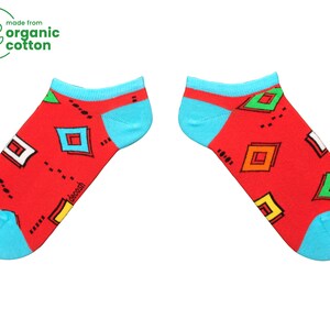 May include: A pair of red ankle socks with a geometric pattern in blue, green, yellow, and white. The socks are made from organic cotton.