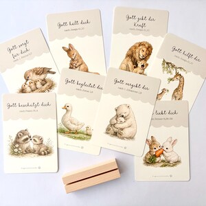 May include: A collection of illustrated cards with animal illustrations, including a bird with chicks, a rabbit with a baby rabbit, a lion with a cub, and a giraffe with a baby giraffe. Each card has German text.
