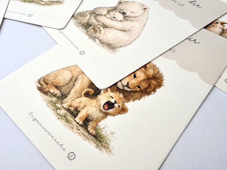 May include: Watercolor illustrations of animals on cards. One card shows a lion and cub, another a polar bear and cub. The cards have a soft, neutral color palette and delicate details, with text in a script font.