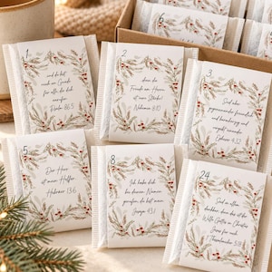 May include: A set of small rectangular packets in a cardboard box, each featuring a white label with a numbered calendar day, a botanical wreath illustration with red berries, and German Bible verses printed in black script.