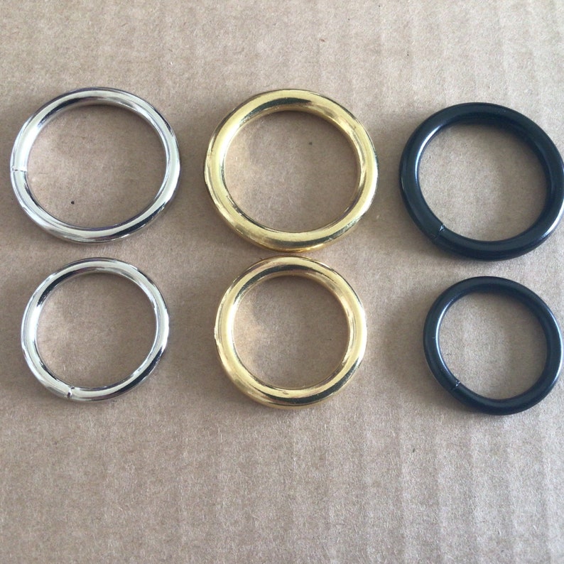 May include: Six metal rings in different sizes and colors. Two silver rings, two gold rings, and two black rings.