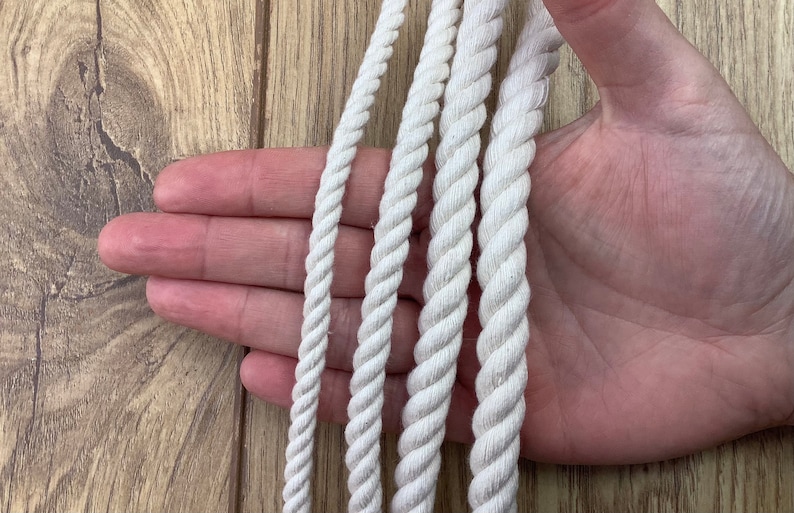May include: Four different sizes of white cotton rope, displayed on a hand.