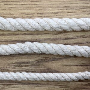 May include: Three white cotton ropes of different thicknesses, laid out on a wooden surface.
