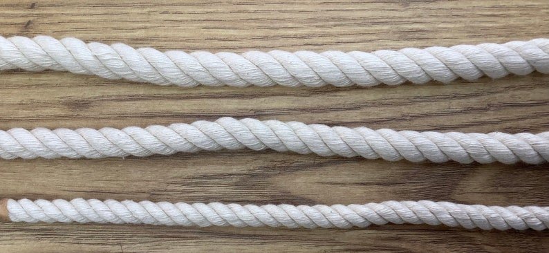 May include: Three white cotton ropes of different thicknesses, laid out on a wooden surface.