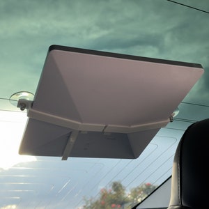 Peut inclure: Support de pare-brise de voiture blanc avec ventouses tenant une tablette blanche.