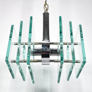 Peut inclure: Un lustre moderne en chrome et en verre avec plusieurs panneaux rectangulaires en verre. Les panneaux sont dispos&eacute;s en quinconce et sont maintenus par un cadre en chrome.